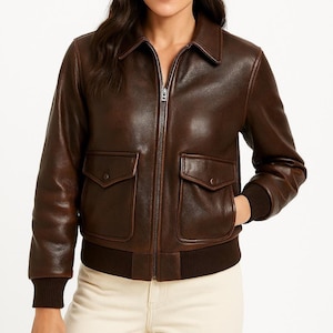 May include: A brown leather bomber jacket with a zip-up front, two front pockets, and a ribbed hem and cuffs. The jacket has a classic collar and a tailored fit, suitable for various occasions.