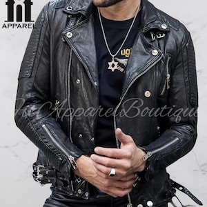 Puede incluir: Chaqueta de cuero negra estilo motero con cremalleras plateadas, broches y cintur&oacute;n con hebilla. La chaqueta tiene un estilo motero cl&aacute;sico con detalles acolchados en los hombros y cuello con solapas. Tambi&eacute;n se ve el texto "Apparel Boutique".