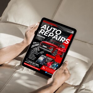 May include: A tablet screen displaying an advertisement for auto repair services. The ad features a red car, a wrench, and the text "AUTO REPAIRS" in bold red letters. The ad also includes a phone number, website address, and a call to action to "BOOK NOW".