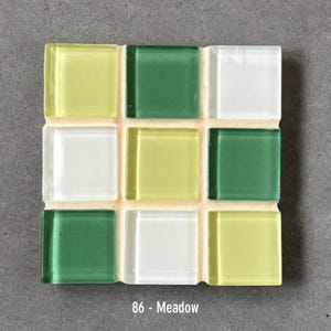 May include: A square mosaic tile sample with nine glass tiles in a grid pattern. The tiles are in shades of green, yellow, and white. The text "86 - Meadow" is at the bottom. The tiles are set against a gray background.