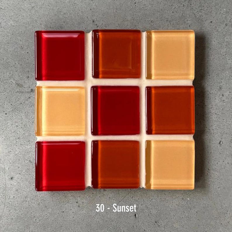 May include: A square mosaic tile sample with nine glass tiles in shades of red, orange, and yellow. The tiles are arranged in a 3x3 grid, with the text "30 - Sunset" at the bottom. The tiles are set on a white backing.