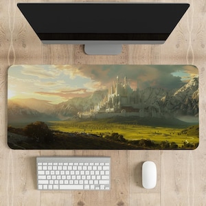 以下が含まれることがあります： 大きな城、山、緑の谷があるファンタジーの風景が描かれた長方形のマウスパッド。画像は、背景に夕日がある暖かい色調です。白いキーボードとマウスがコンピューターモニターの下にあります。
