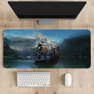 Peut inclure: Tapis de souris rectangulaire avec une illustration détaillée de deux personnages dans un bateau sur un lac, avec une montagne en arrière-plan. Le tapis de souris a une bordure noire et est associé à un clavier et une souris blancs.