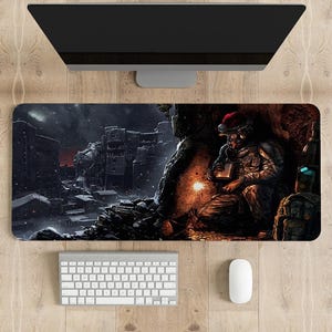 May include: A black and white gaming mousepad featuring a soldier in a winter scene. The soldier is wearing camouflage and a Santa hat. He is holding a weapon and a torch. The background is a snowy city.