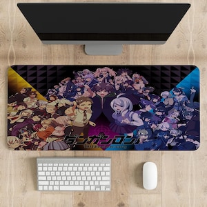 May include: A rectangular desk mat featuring a vibrant, multi-character anime illustration with a dark background. The design includes the Japanese text "ダンガンロンパ" and the English text "10th Anniversary" centred at the bottom of the mat.