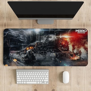 May include: Rectangular mouse pad featuring a detailed illustration of a train, figures in gas masks, and the text "Metro Exodus." The artwork is set against a backdrop of a stormy sky and industrial structures. A keyboard and mouse are visible.