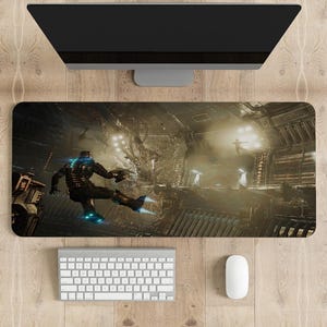 May include: A rectangular gaming mousepad featuring a sci-fi scene with a figure in a spacesuit. The image shows a futuristic interior with a character in action. A keyboard, mouse, and monitor are visible.