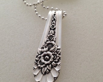 May include: A silver necklace with a pendant made from a vintage silverware spoon with a floral design.