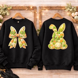 Pode incluir: Duas camisolas pretas com designs de Páscoa. Uma apresenta um grande laço com retalhos verdes, laranja e amarelos. A outra mostra um coelho de retalhos com um laço. Ambos os designs têm uma aparência acolchoada, perfeitos para a época da primavera.