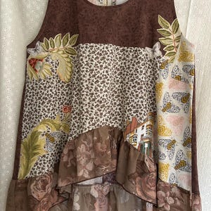 Può includere: Un top senza maniche patchwork con un motivo floreale marrone, una stampa floreale color crema e un orlo a balze floreale. Il top presenta uno scollo tondo e una chiusura con cerniera. Il design include foglie ricamate, farfalle e una scena di edificio.