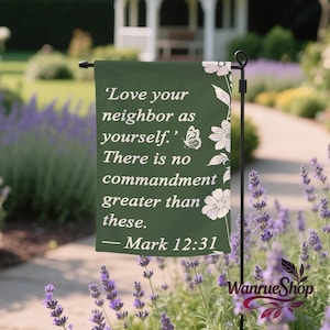 Könnte beinhalten: Eine rechteckige dunkelgrüne Gartenflagge mit dem weißen Text 'Love your neighbor as yourself. There is no commandment greater than these. — Mark 12:31' und einer weißen Blumen- und Schmetterlingsillustration am rechten Rand.