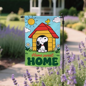 May include: A rectangular garden flag featuring a cartoon dog sitting in a yellow doghouse with a red roof. A small yellow bird sits on the roof under a bright sun. The text Home sweet HOME is printed in red and green letters on a green grass base.