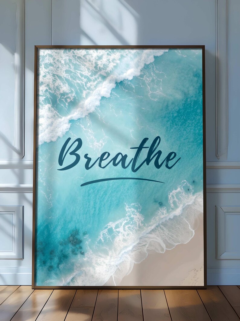 May include: Framed wall art featuring an aerial view of ocean waves in shades of turquoise and white, crashing onto a sandy beach. The word "Breathe" is written in a cursive font across the image.