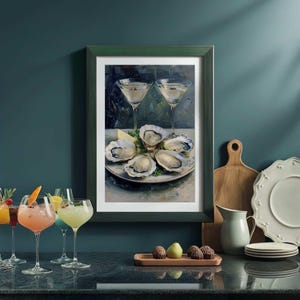 May include: A framed print of a still life featuring oysters on a plate with lemon and two martini glasses. The print is in a green frame. Several cocktails are in the foreground.