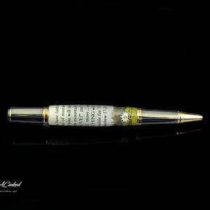May include: A silver and gold pen with a decorative barrel featuring text and a floral design. The pen has a gold tip and a black background. The text on the barrel reads "have faith...move...THING".