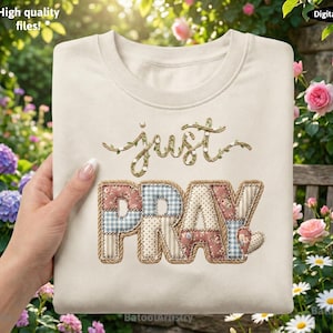 Könnte beinhalten: Cremefarbenes Sweatshirt mit dem gestickten Schriftzug "just PRAY" in einem Patchwork-Design. Die Buchstaben sind in floralen, Vichy- und gepunkteten Mustern gehalten, mit einem Herz-Akzent. Das Wort "just" ist kursiv mit einem Blätterdesign geschrieben.