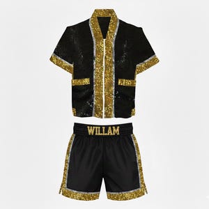 Könnte beinhalten: Schwarzes Box-Robe- und Shorts-Set mit goldfarbenen Paillettenbesatz. Die Robe hat kurze Ärmel und Taschen. Auf den Shorts steht der Name "WILLAM" am Bund.