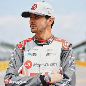 Puede incluir: Una persona con un traje de carreras blanco y gris con detalles rojos, con el logotipo de MoneyGram. La persona tambi&eacute;n lleva una gorra blanca con un logotipo rojo y un reloj negro. El fondo es un circuito.
