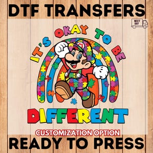May include: DTF Transfers design featuring a colorful illustration of Mario from the Super Mario Bros. series. The image includes the text "It's Okay to Be Different" and "Ready to Press". The design incorporates a rainbow and puzzle pieces.