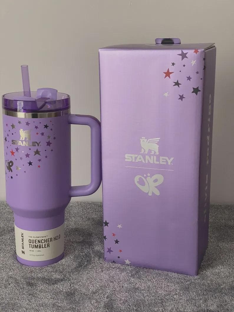 Peut inclure: Un gobelet Stanley Quencher H2.0 lavande avec une poign&eacute;e, une paille et un couvercle, &agrave; c&ocirc;t&eacute; d'une bo&icirc;te assortie. Le gobelet et la bo&icirc;te sont d&eacute;cor&eacute;s de motifs d'&eacute;toiles et du logo Stanley. Le gobelet est con&ccedil;u pour une hydratation tout au long de la journ&eacute;e.