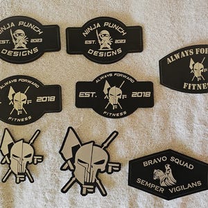 May include: A selection of black and white patches with different designs and text. The patches display phrases such as "Ninja Punch Designs," "Always Forward Fitness," and "Bravo Squad." Some patches include the year "2018" or "2023."