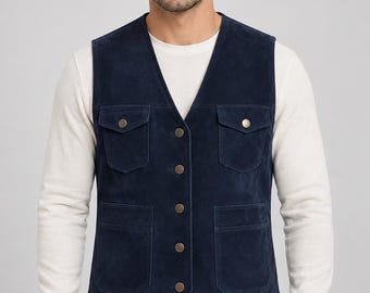 May include: A navy blue suede vest featuring a V-neckline, a front button closure with metallic buttons, two chest pockets with buttoned flaps, and two lower patch pockets. The vest is worn over a long-sleeved white shirt and black pants.
