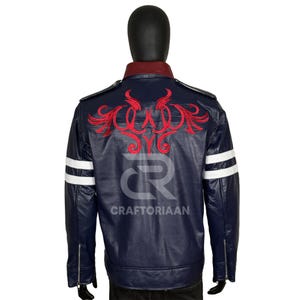 Könnte beinhalten: Marineblaue Lederjacke mit rotem Kragen und roter Stickerei auf dem Rücken. Die Ärmel haben weiße Streifen und der Text "CRAFTORIAAN" ist sichtbar.