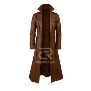 Pode incluir: Um trench coat de couro marrom com gola larga, ombreiras e cinto na cintura. O casaco comprido tem um design clássico e é feito de um material liso e castanho escuro. O casaco está aberto, revelando o forro interior.