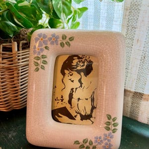 May include: A white ceramic mug with a black handle and the text "But First, Coffee" in a bold, black font. The mug is set against a blurred background, suggesting a cozy setting.