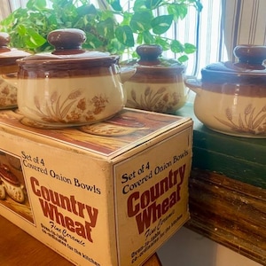 May include: Set of four brown and beige ceramic covered onion bowls with a wheat design. The bowls are on a box that says "Country Wheat Fine Ceramic Oven-to-table cookware for the kitchen".