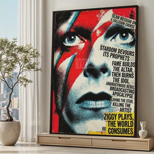 Może przedstawiać: Oprawiony plakat z wystylizowanym portretem z czerwoną i niebieską farbą do twarzy. Plakat zawiera tekst: "STARDOM DEVOURS ITS PROPHETS" i "ZIGGY PLAYS, THE WORLD CONSUMES". Grafika jest eksponowana na drewnianej szafce.