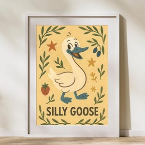 May include: Framed art print featuring a cartoon goose with a smiling face, blue beak, and blue feet. The goose is set against a yellow background with green leaves, stars, and a strawberry. The words "SILLY GOOSE" are below the goose.