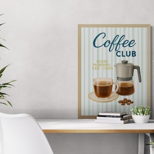 May include: A framed poster with a coffee theme. The poster features a coffee maker, a cup of coffee, and the words "Coffee Club" with the time "Every Morning 7 AM - 10 AM". The poster is on a white desk with plants.