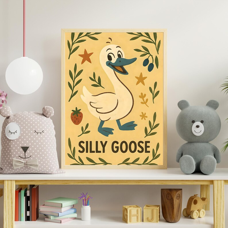 May include: A framed print featuring a cartoon goose with the text "SILLY GOOSE" on a yellow background. The goose is cream-colored with blue feet and beak. The print is decorated with stars, leaves, and a strawberry.