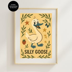 May include: A framed print featuring a cartoon goose with a smiling expression, blue beak and feet, and white feathers. The print has the words "SILLY GOOSE" in a playful font, surrounded by leaves, stars, and a strawberry on a yellow background.