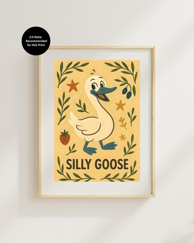 May include: A framed print featuring a cartoon goose with a smiling expression, blue beak and feet, and white feathers. The print has the words "SILLY GOOSE" in a playful font, surrounded by leaves, stars, and a strawberry on a yellow background.