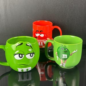 M&M'sの赤または緑の陶器製マグカップ。食器洗い機と電子レンジに対応