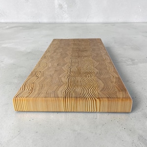 May include: A rectangular wooden chopping board with a light brown, end-grain pattern. The board has a smooth surface and a natural wood grain appearance. The edges are clean and the board is set against a neutral background.