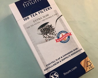May include: A blue and white box of 100 extra slim tea filters. The box features the finum logo and the text "100 Tea Filters Extra Slim 100 Tee Filter / 100 Filtres à Thé". The box also features a small image of a tea bag with loose tea leaves.