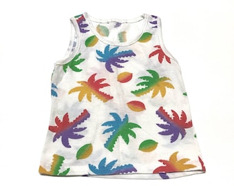 May include: White sleeveless tank top with a colorful tropical print of palm trees and fruit. The print features a rainbow color scheme.