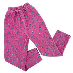 Op de afbeelding: Roze corduroy broek met een elastische tailleband en een kleine strik. De broek is bedrukt met kleine blauwe bloemmotieven. De broek is gemaakt van zacht corduroy materiaal.