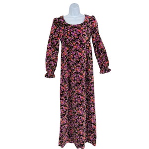 May include: A long-sleeved, floor-length dress with a square neckline. The dress features a black background covered in a floral pattern of pink, purple, and orange flowers. The sleeves end in ruffled cuffs.