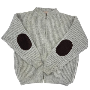 May include: A light gray zip-up sweater with ribbed knit texture and dark brown elbow patches. The sweater has a high collar and a full-length zipper. A classic, comfortable garment for cooler weather.