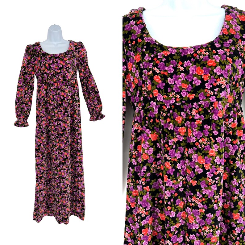 May include: A long-sleeved, floor-length dress with a scoop neckline. The dress features a black background covered in a floral pattern of purple, pink, and orange flowers. The sleeves end in ruffled cuffs. The dress is displayed on a white mannequin.