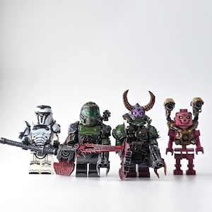 May include: Four custom minifigures inspired by the video game Doom, standing in a row. The figures are in various colours, including white, green, and red. Each figure is holding a weapon or has unique armour and accessories.