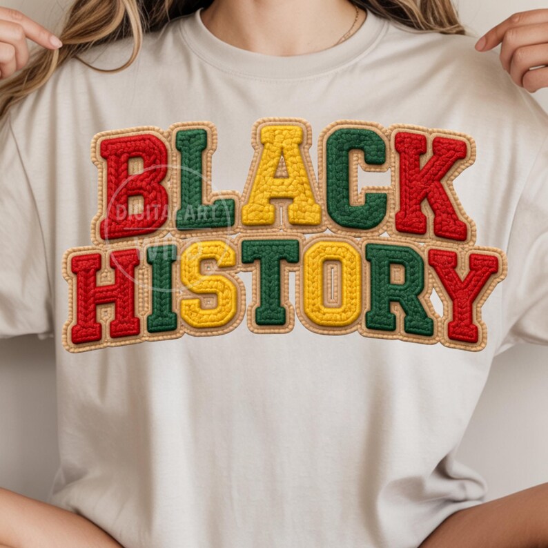 May include: A cream-colored t-shirt featuring the words "BLACK HISTORY" in a bold, textured design. The text is in red, yellow, and green, with a stitched appearance, and a tan border. The shirt is a casual style.