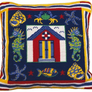 May include: Square decorative pillow with a nautical theme. The navy blue pillow features a central design of a red beach hut with blue and yellow accents, surrounded by seahorses, starfish, and seashells. The border is striped with red, white, and yellow.