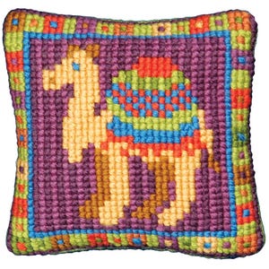 May include: A square, handmade needlepoint pillow featuring a camel design. The camel is in shades of tan, with a colorful saddle in blue, green, and red. The background is purple, and the border is a mix of colors, including green, blue, orange, and red.