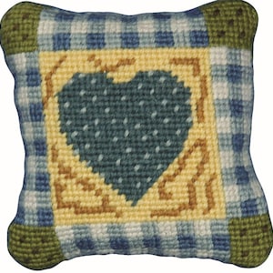 May include: A square, handmade pillow with a blue and white gingham pattern. The center features a teal heart with white dots, framed by a yellow border with brown accents. The corners are green.