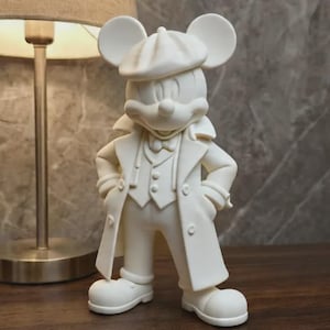 Könnte beinhalten: Eine mattweiße Figur einer Cartoon-Maus, die eine Schiebermütze, einen langen Trenchcoat, eine Weste und eine Fliege trägt. Die Figur steht mit den Händen in den Hüften und zeichnet sich durch große, runde Ohren und eine glatte Oberfläche aus.